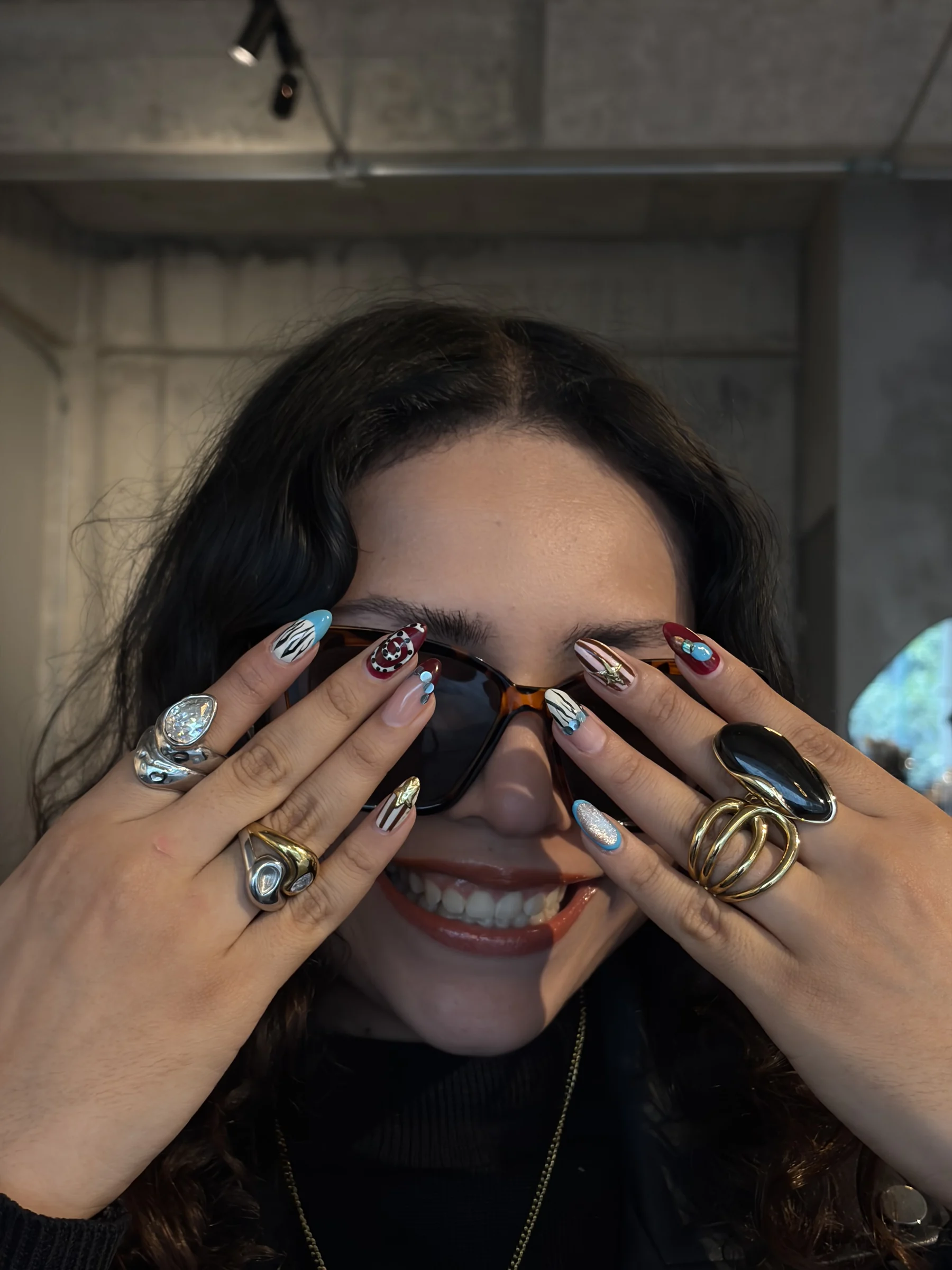 Alessa sonriendo con las manos frente a la cara, enseñando sus uñas