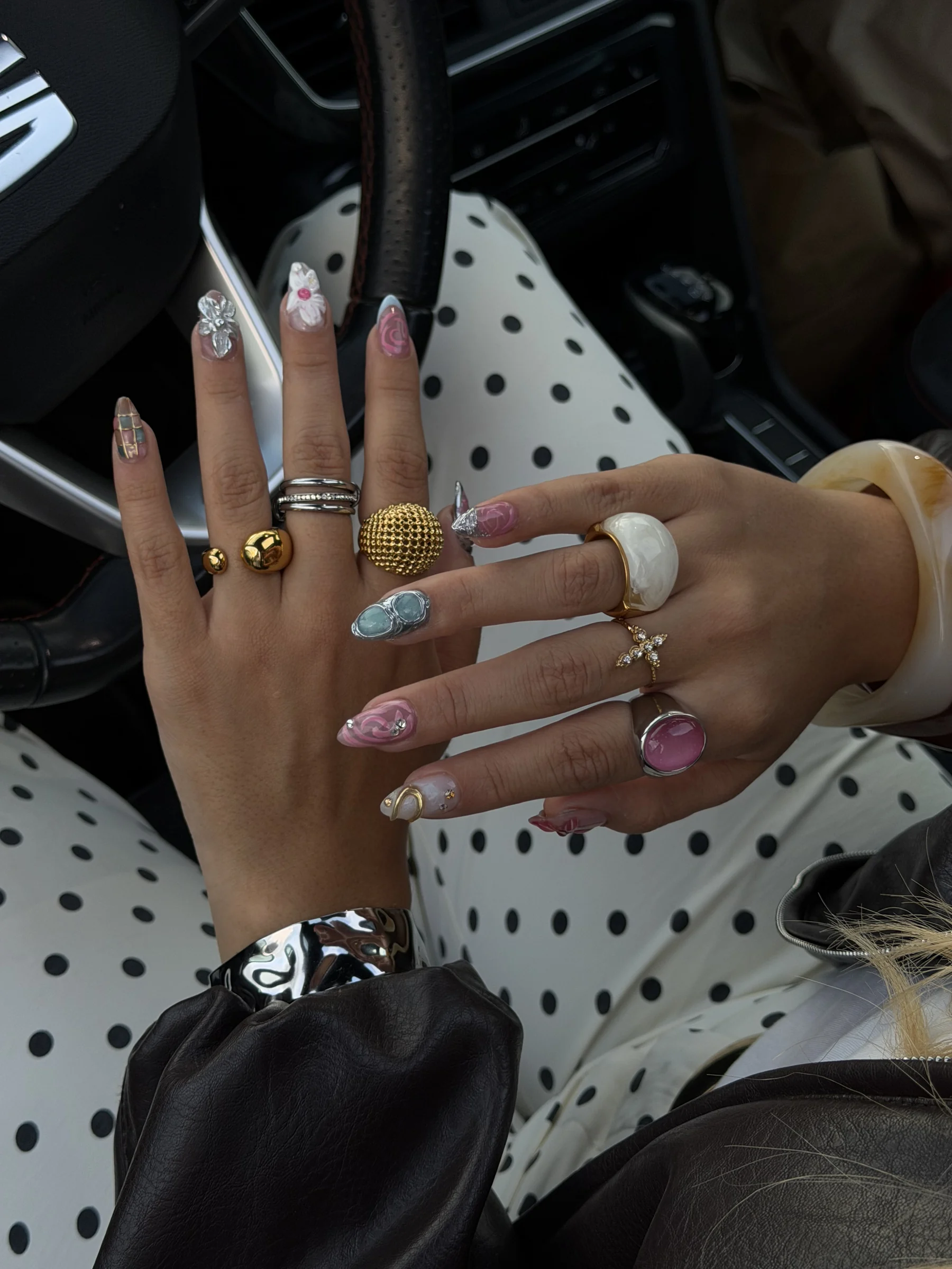Uñas largas de softgel con diseños y anillos, sobre un pantalón de lunares